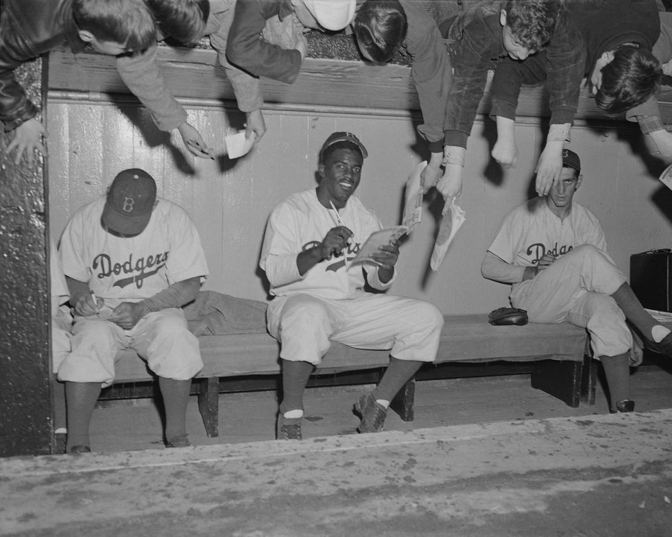 Jackie Robinson and teammates signing autographs for fans in 1949