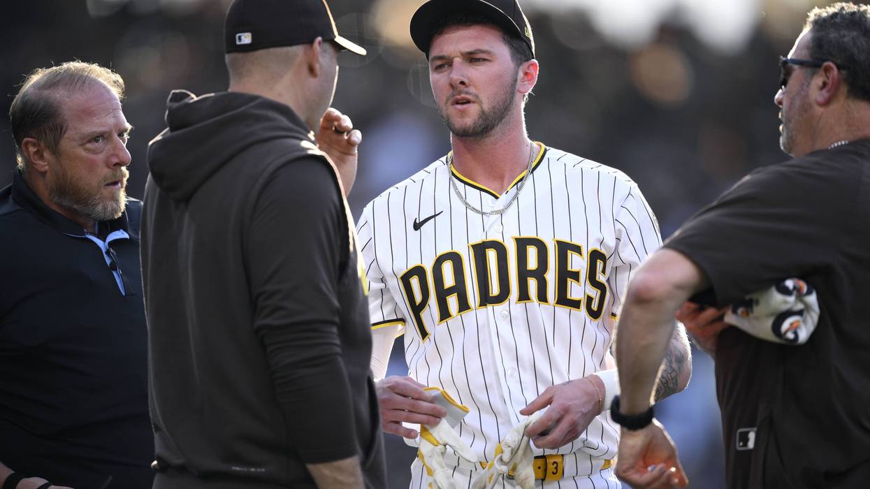 Jackson Merrill #3 of the San Diego Padres talks to manager Craig Stammen #14 and a trainer after striking out during the second inning against the Los Angeles Dodgers at Petco Park on May 20, 2026 in San Diego, California