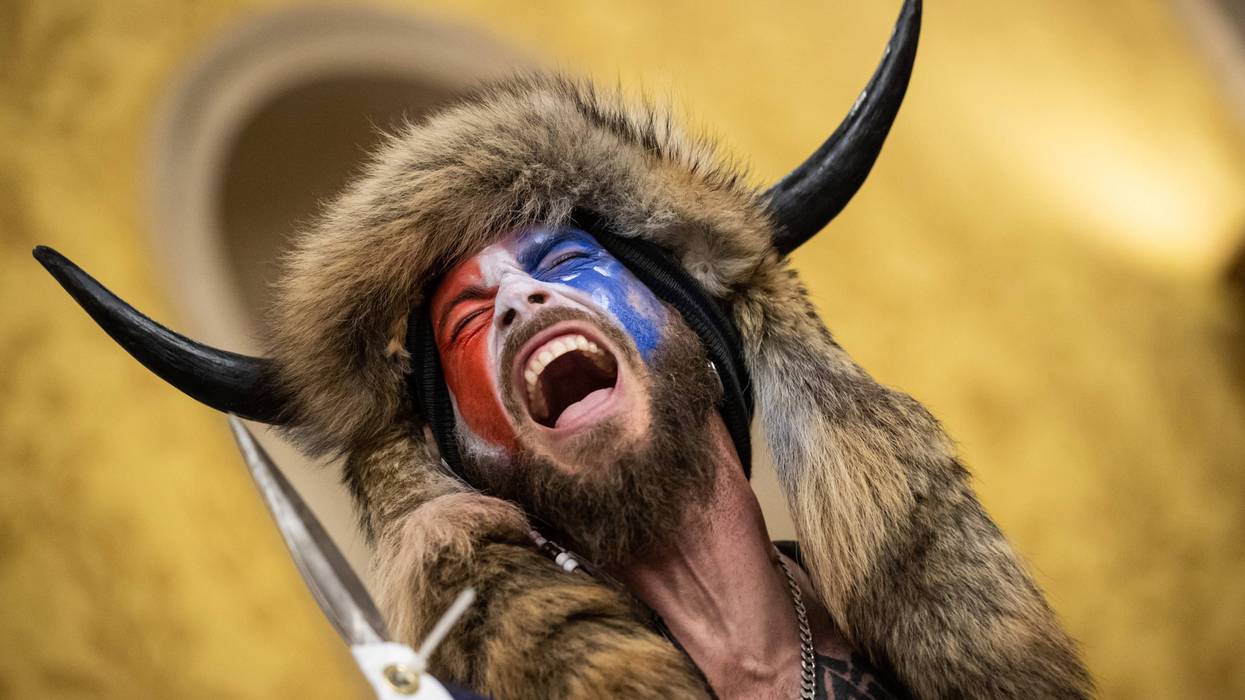 jacob chansley on jan 6 with his face painted, his bull horns, and his flag which appears to be sharpened at the tip
