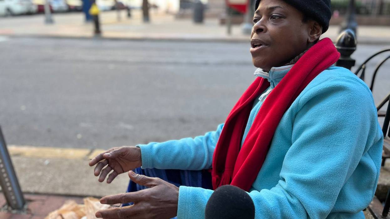 jada davis speaks into a kmox microphone. she's a black woman with a blue jacket, red scarf, and black beanie