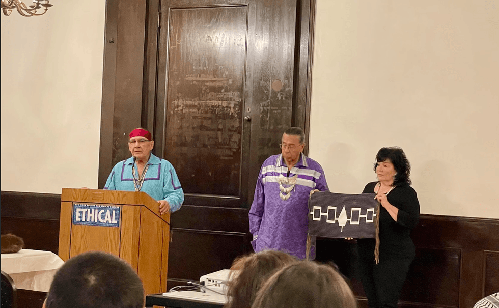 Jake Edwards (at the podium), Onondaga Chief, Tadodaho Sid Hill and Betty Lyons holding the Hiawatha Belt, the national belt of the Haudenosaunee, on Nov. 20, 2024, at the New York Society for Ethical Culture.