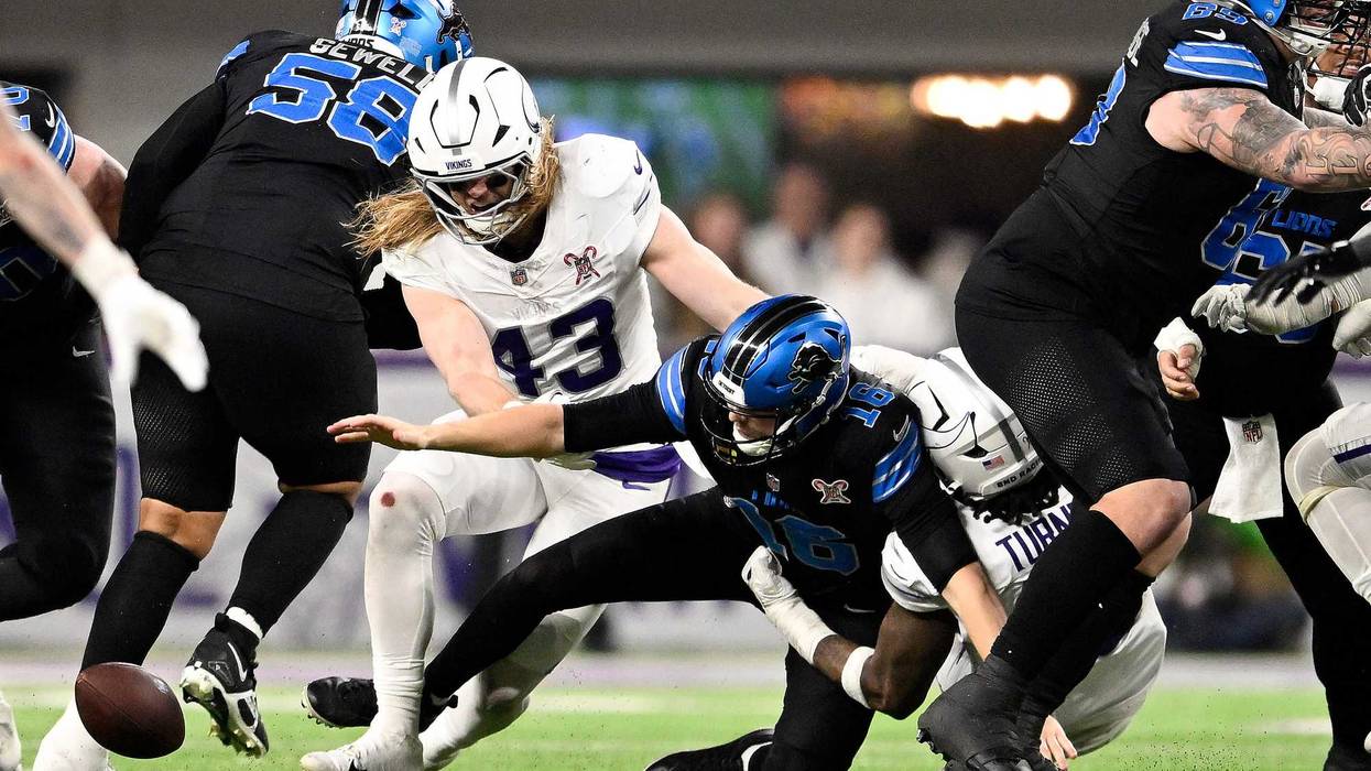 Jared Goff #16 of the Detroit Lions fumbles the ball against Dallas Turner #15 and Andrew van Ginkel #43 of the Minnesota Vikings during the fourth quarter at U.S. Bank Stadium on December 25, 2025 in Minneapolis, Minnesota.
