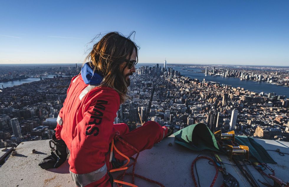 Jared Leto, clad in his skyscaper-climbing gear, sits on a ledge on the Empire State Building on Nov. 9, 2023, as part of a promotion for his band Thirty Seconds to Mars