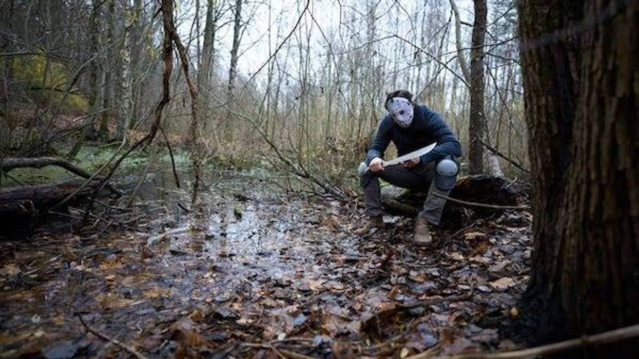 Jason Voorhees in hockey mask and machete sitting on the swamp