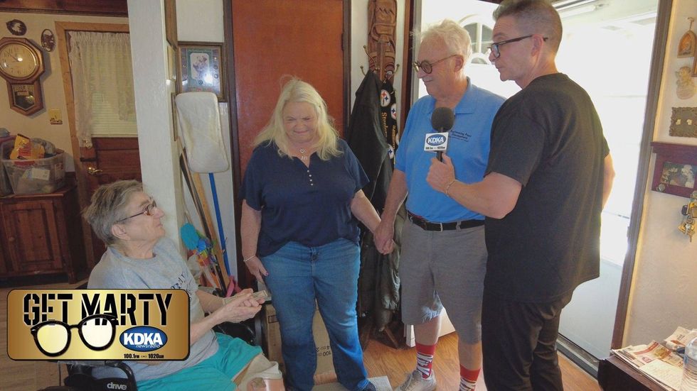 Jeanie and Dale Kleiner join Marty Griffin to deliver a surprise check for $1,000