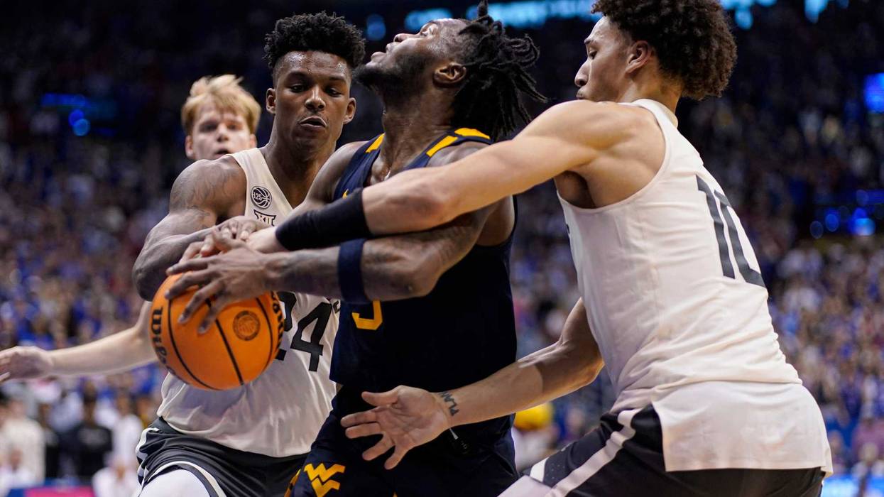Joe Toussaint #5 of the West Virginia Mountaineers has the ball stripped away by K.J. Adams Jr. #24 and Jalen Wilson #10 of the Kansas Jayhawks in the second half at Allen Fieldhouse on February 25, 2023 in Lawrence, Kansas.