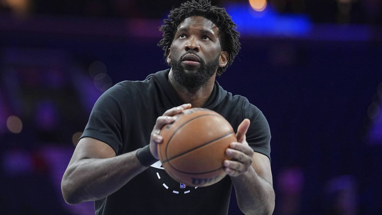 Joel Embiid holds a basketball, looking up with focus on the court.