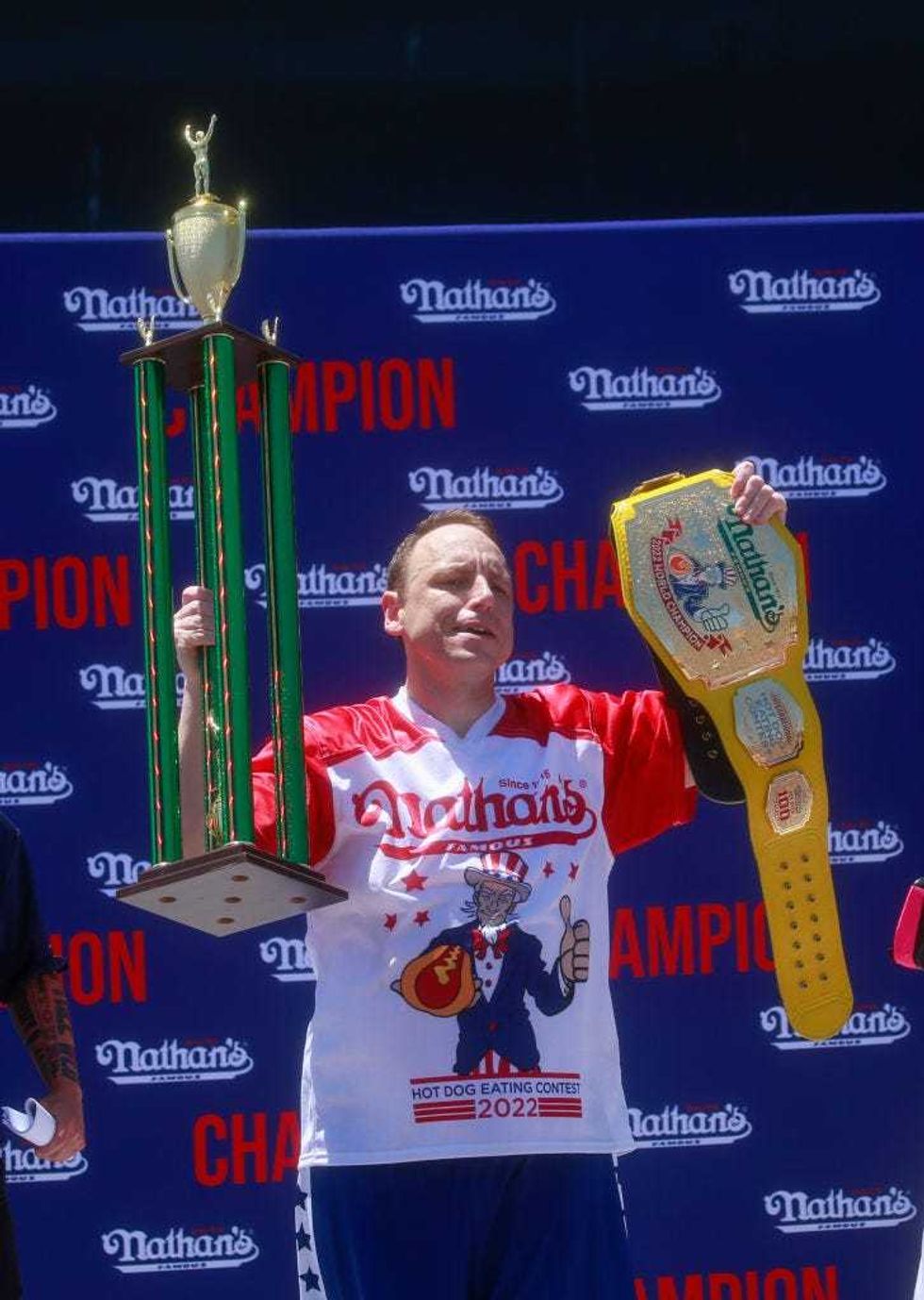 Joey Chestnut holds the trophy and belt after he won first place, eating 63 hot dogs in 10 minutes, during the 2022 Nathan
