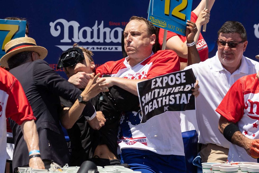 Joey Chestnut tackles a protester who interrupted the competition during the 2022 Nathan