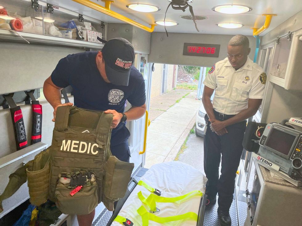 John Chattley (left) holds up a bulletproof medic vest in an ambulance along with Michael Simmons.
