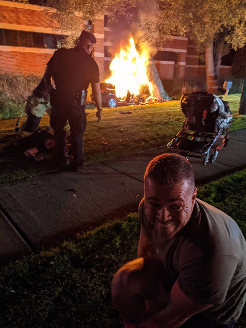 John Leslie kneels to fix his shoe after extricating the man from his burning vehicle