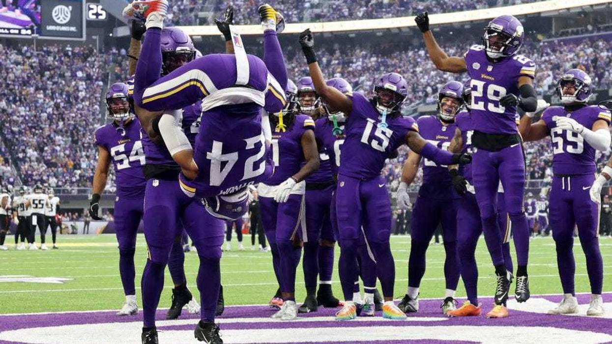 Josh Metellus #44 of the Minnesota Vikings flips teammate Camryn Bynum #24 after intercepting a pass against the Atlanta Falcons during the second quarter at U.S. Bank Stadium on December 08, 2024 in Minneapolis, Minnesota.