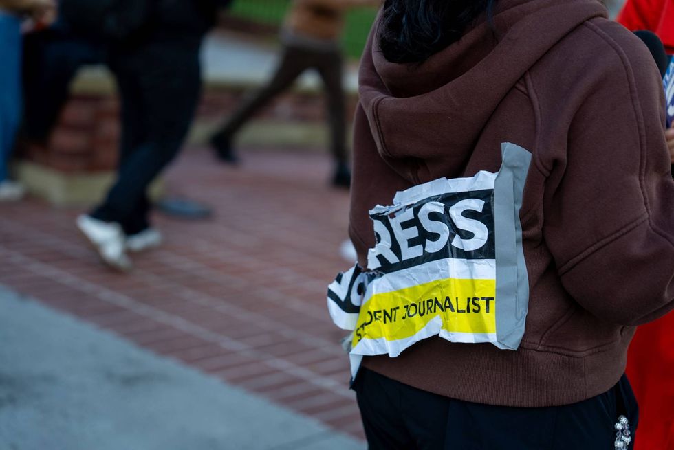 journalist with paper press sign taped to back