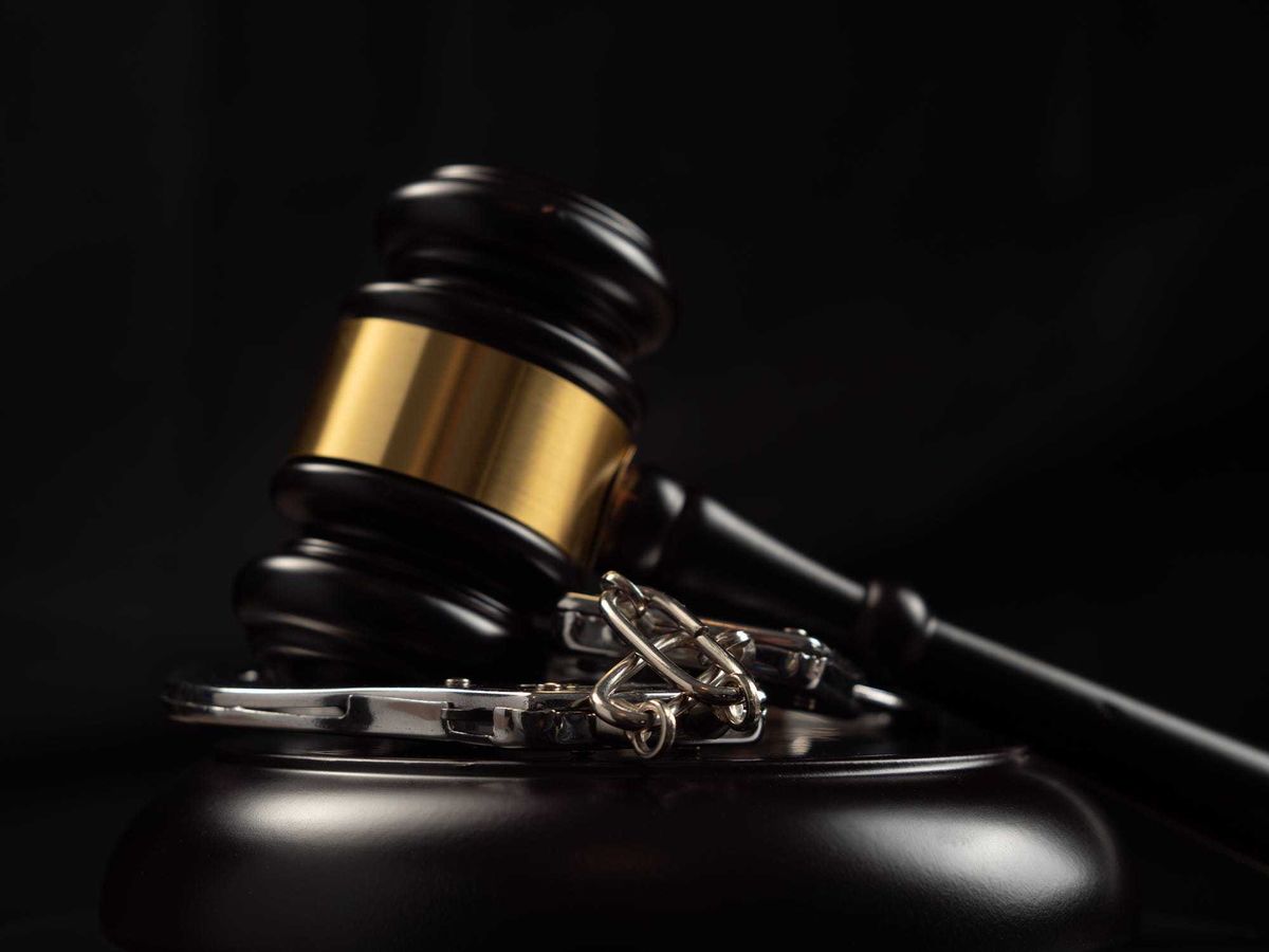 Judge's gavel and handcuffs on a dark background. Judge's gavel and handcuffs close-up.