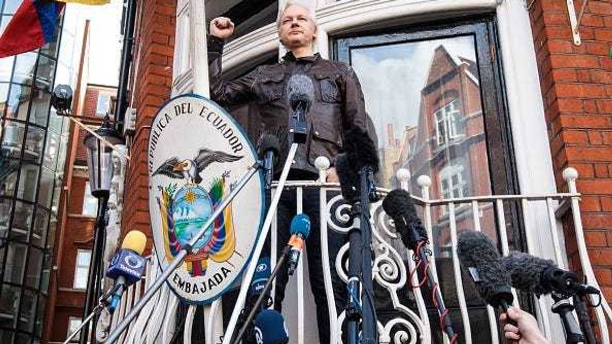 Julian Assange puts his fist in the air as he steps out to speak to the media from the balcony of the Embassy Of Ecuador on May 19, 2017