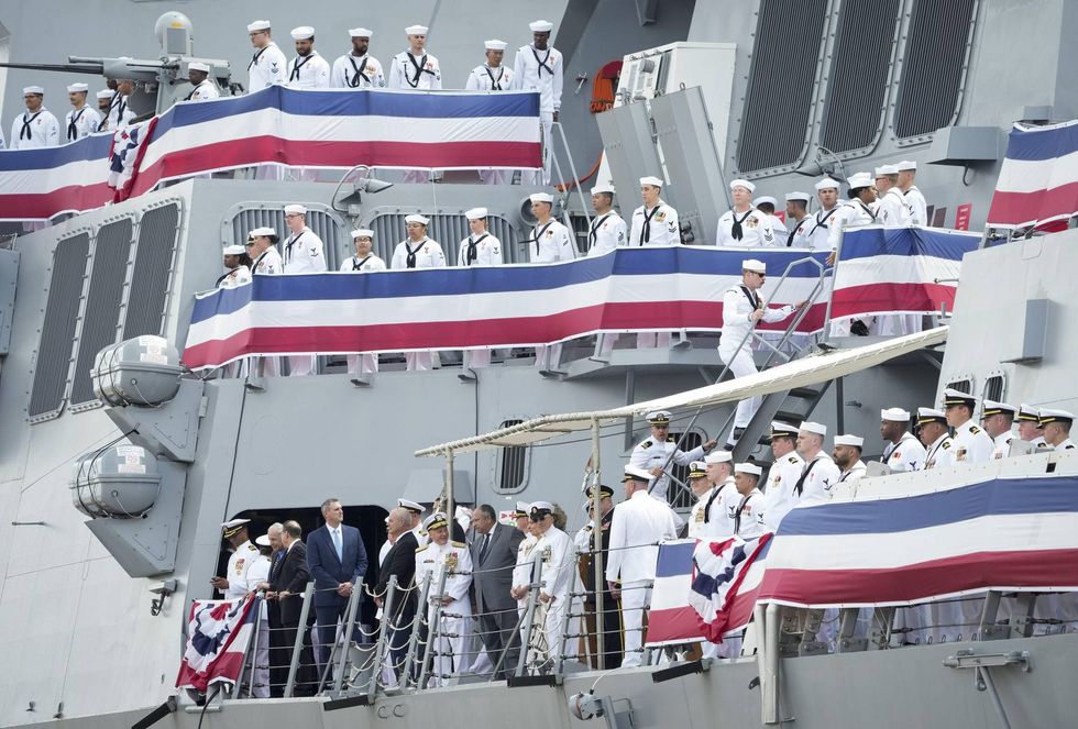 Jun 24, 2023; Baltimore, MD, USA; Secretary of the United States Navy Carlos Del Toro, grey suit, watches as the crew mans the ship during the commissioning ceremony for the USS Carl M. Levin (DDG 120) in Baltimore, MD on Saturday, June 24, 2023