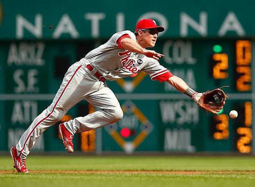 June 13, 2015: Chase Utley of the Phillies flips the ball to first base against the Pirates in Pittsburgh, Pennsylvania.