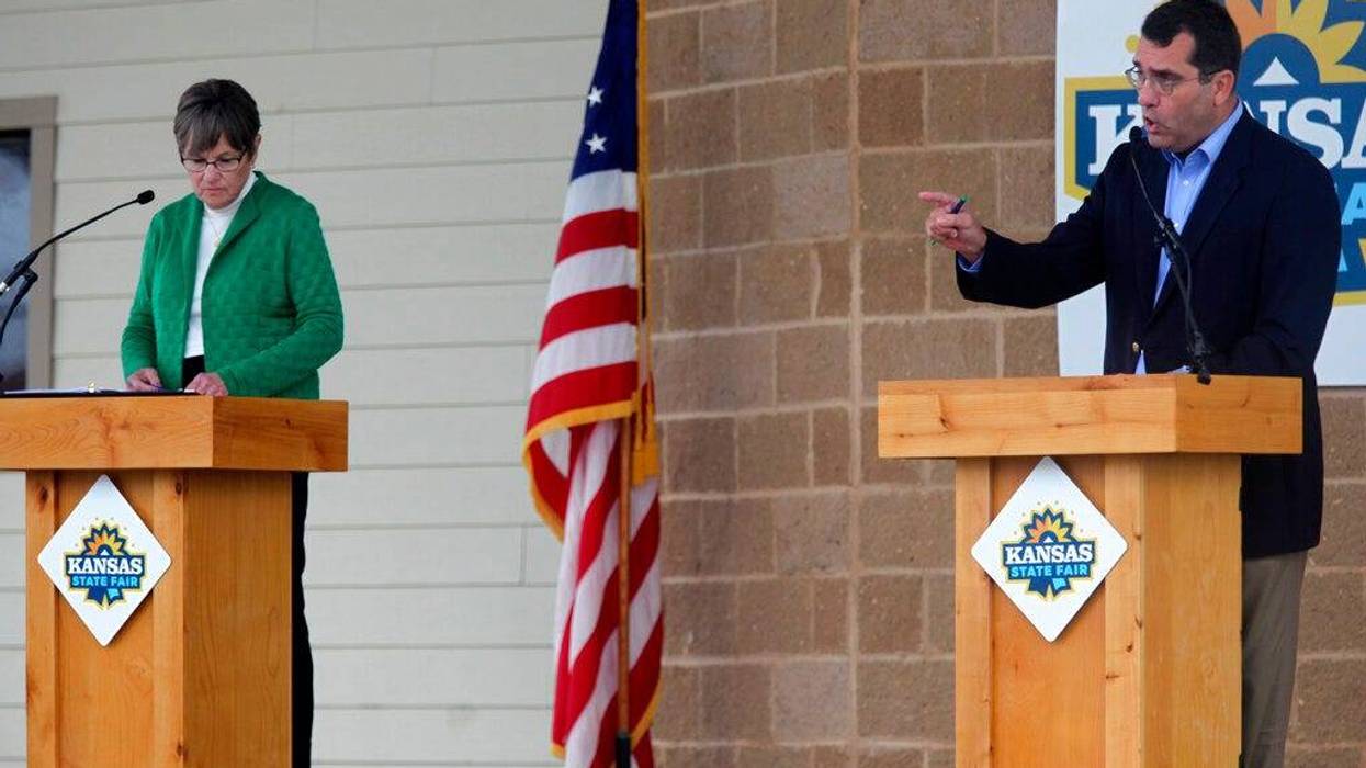 Kansas Attorney General Derek Schmidt, right, the Republican nominee for governor, makes a point during a debate as Democrat Gov. Laura Kelly watches at the Kansas State Fair.