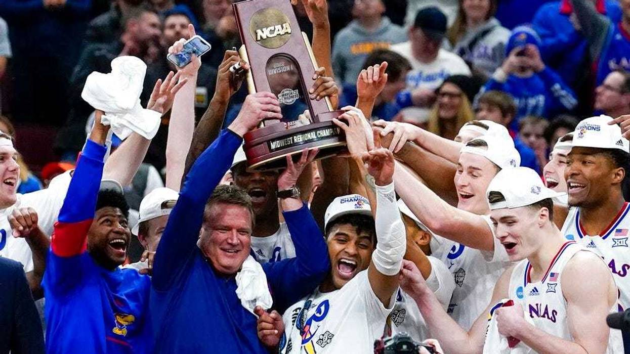Kansas head coach Bill Self and players hold up the winning trophy after a college basketball game in the Elite 8 round of the NCAA tournament against Miami
