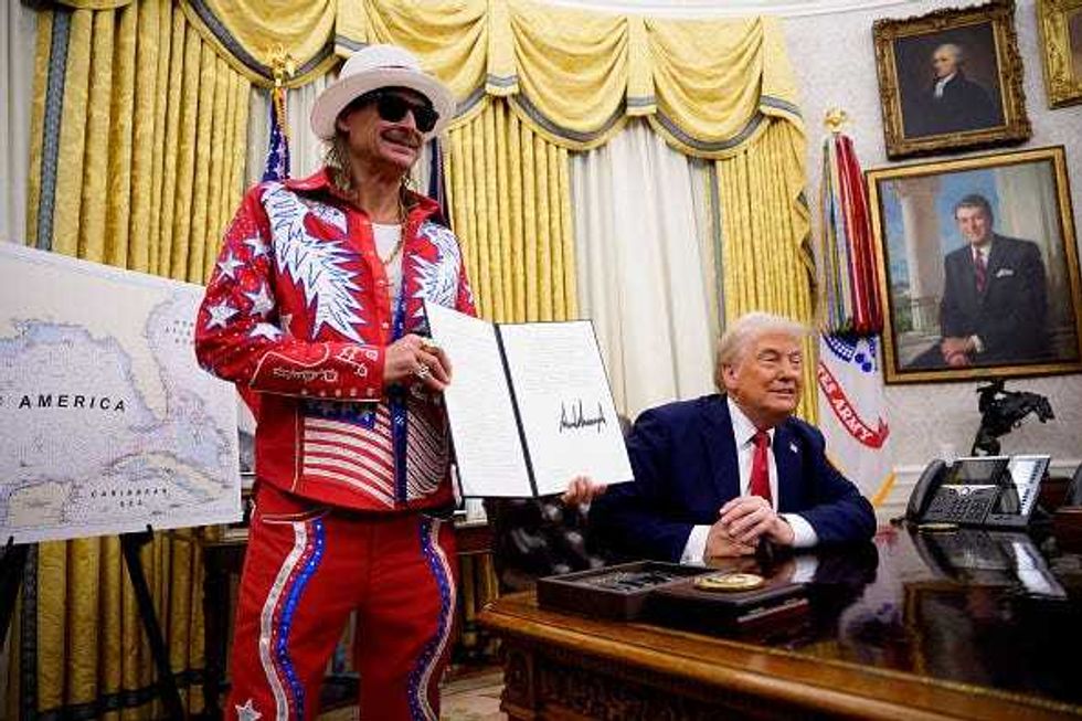 Kid Rock at the White House with President Trump, holds up executive order regarding ticket scalping