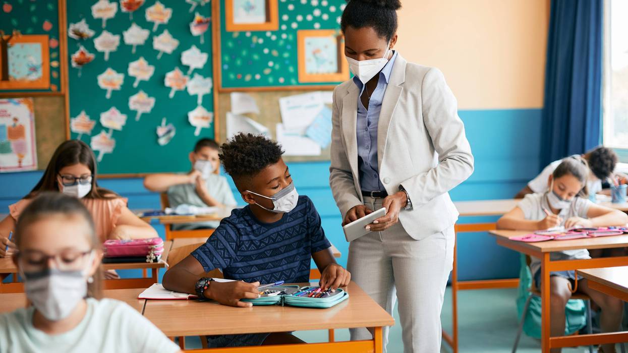 kids in a classroom with a teacher wearing masks