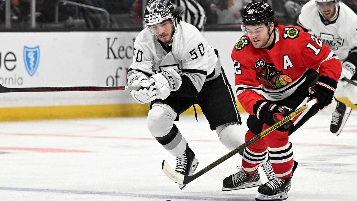 Kings defenseman Sean Durzi (50) and Blackhawks left wing Alex DeBrincat (12) chase down the puck.