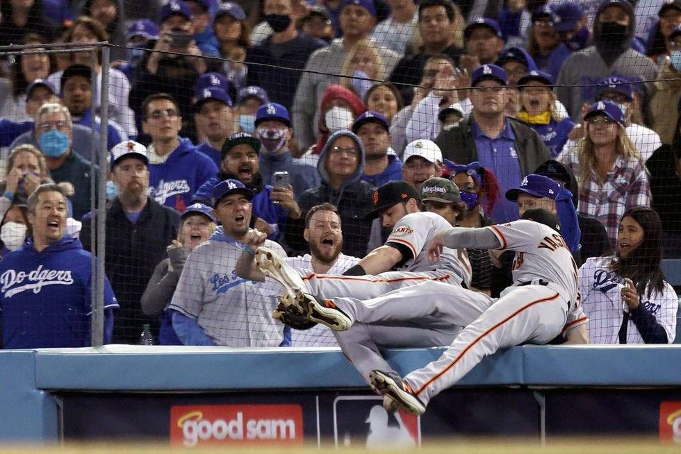 Kris Bryant #23 and Mike Yastrzemski #5 of the San Francisco Giants chase a foul ball by AJ Pollock #11 of the Los Angeles Dodgers during the ninth inning in game 3.