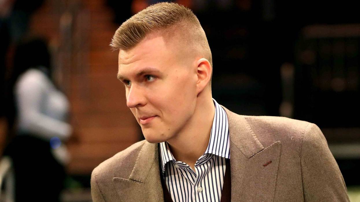 Kristaps Porzingis looks on in street clothes during a New York Knicks game.