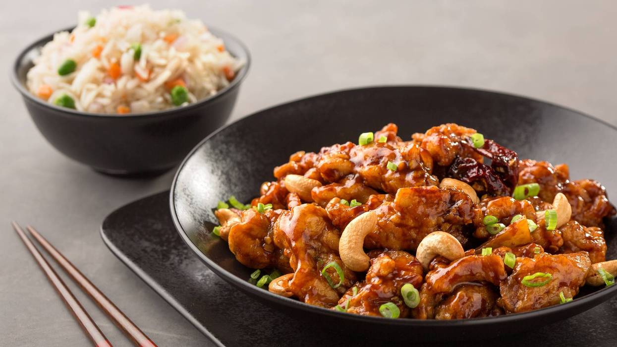 kung pao chicken with chinese rice served in dish isolated on dark background side view