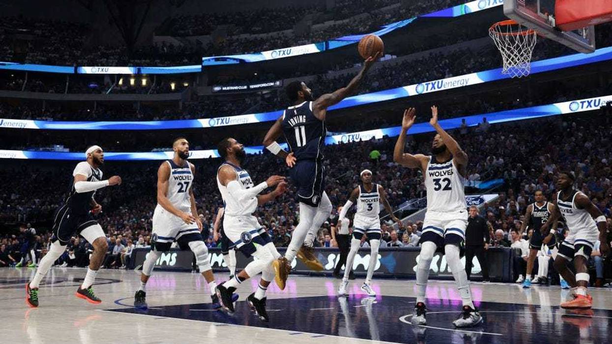 Kyrie Irving #11 of the Dallas Mavericks shoots the ball between Mike Conley #10 and Karl-Anthony Towns #32 of the Minnesota Timberwolves during the second quarter in Game Three of the Western Conference Finals.