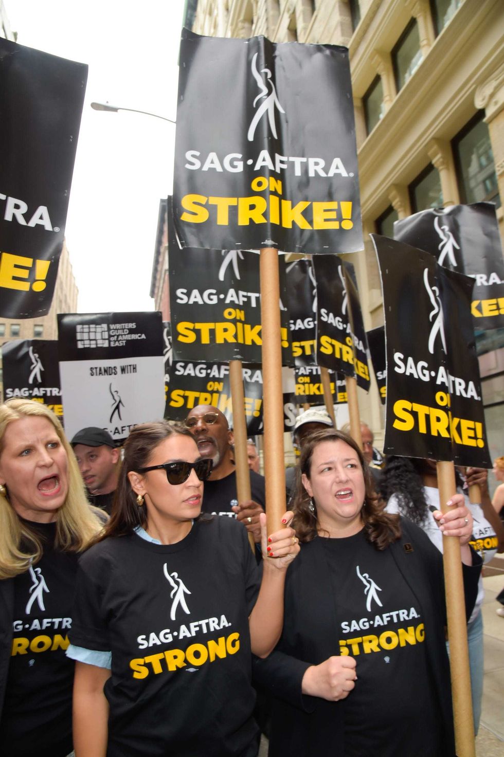 (L-R) AFL-CIO President Liz Shuler and Alexandria Ocasio-Cortez walk the picket line in support of the SAG-AFTRA and WGA strike on July 24, 2023 in New York City.
