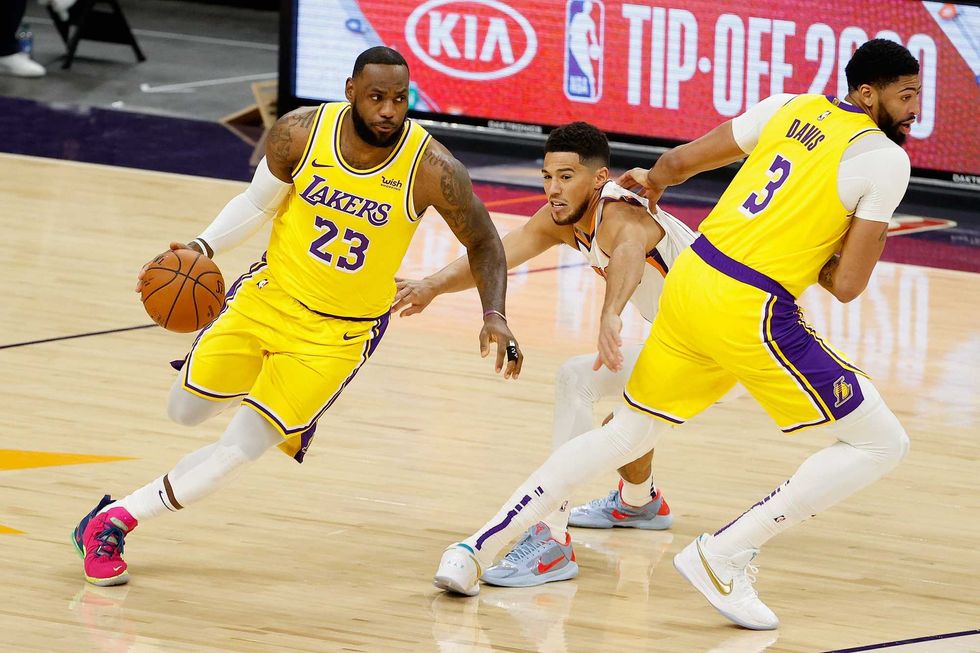 Lakers forward LeBron James drives past Phoenix guard Devin Booker in an NBA preseason game