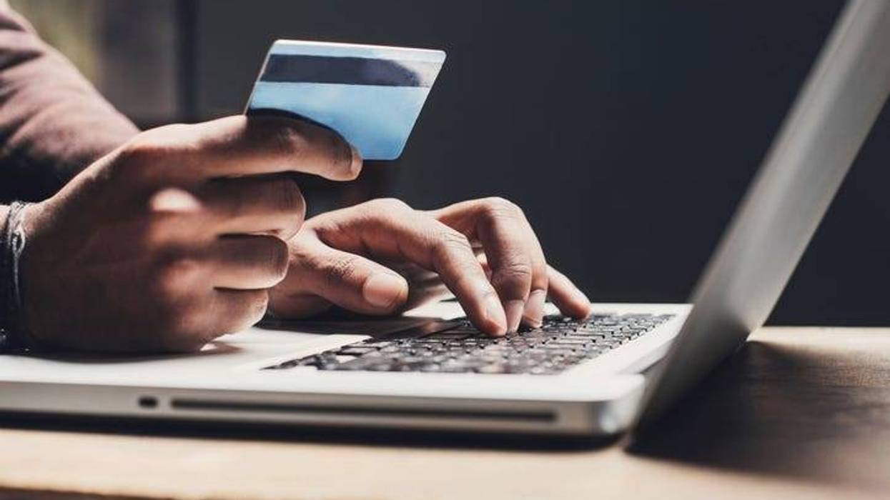 laptop with view of mans hand holding a credit card