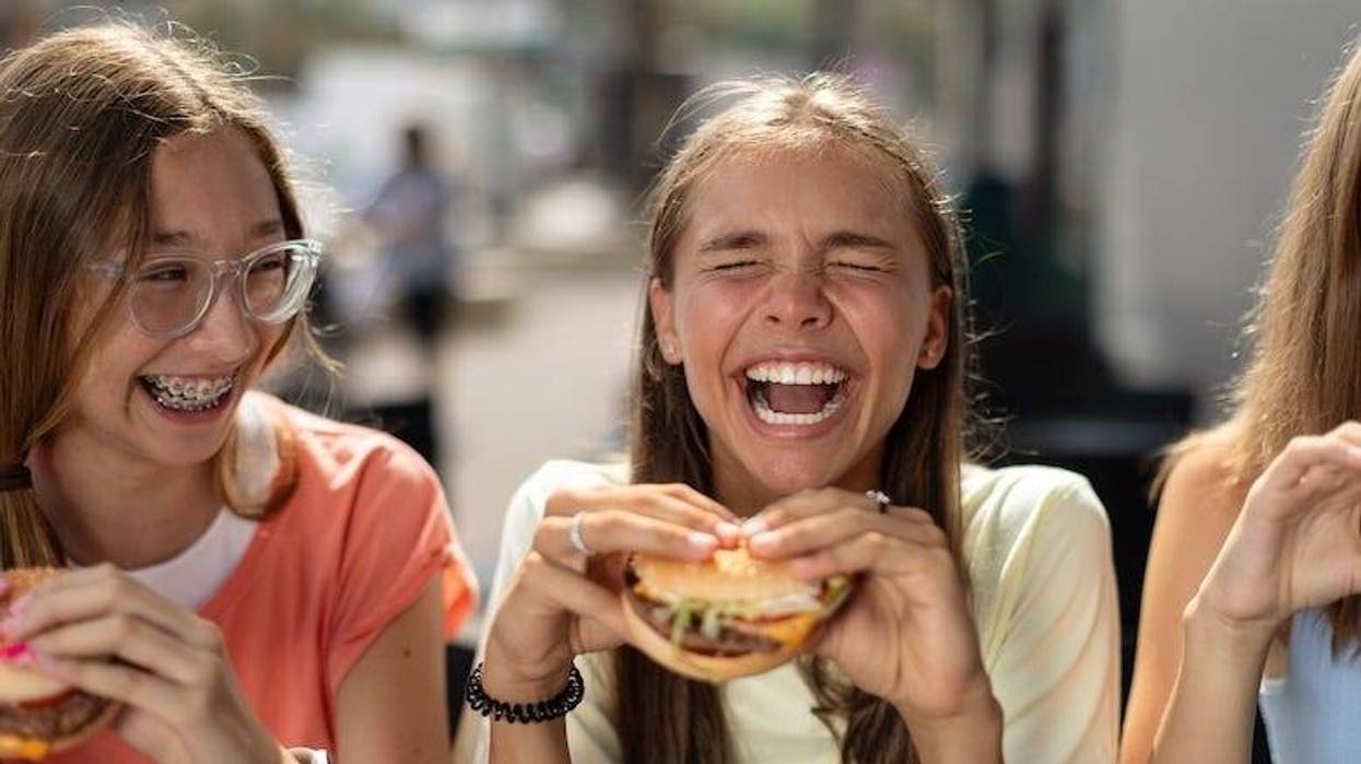 Laughing teenage girls eating hamburgers