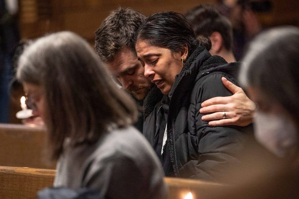 Lauren Enty of Lansing gets emotional while sitting with her husband Ben Rumbaugh of Lansing at the end of a vigil held at Eastminster Presbyterian Church in East Lansing on Tuesday, February 14, 2023, in memory of the students shot and killed during a mass shooting at Michigan State University