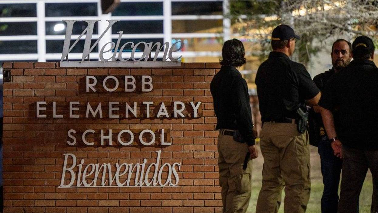 Law enforcement officers speak together outside of Robb Elementary School following the mass shooting at Robb Elementary School