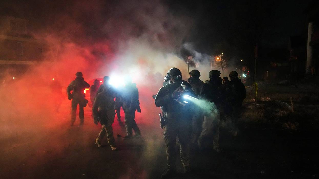 Law enforcement officers stand amid tear gas at the scene of a reported shooting Wednesday, Jan. 14, 2026, in Minneapolis.