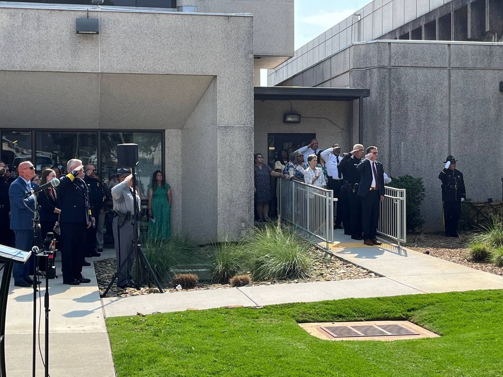 Law enforcement officials saluting during the ceremonial raising of the flag to half mast at the Greenville County Sheriff