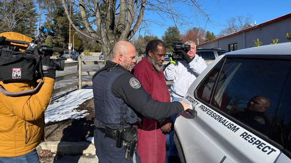 Law enforcement personnel escort Kelvin Roberts