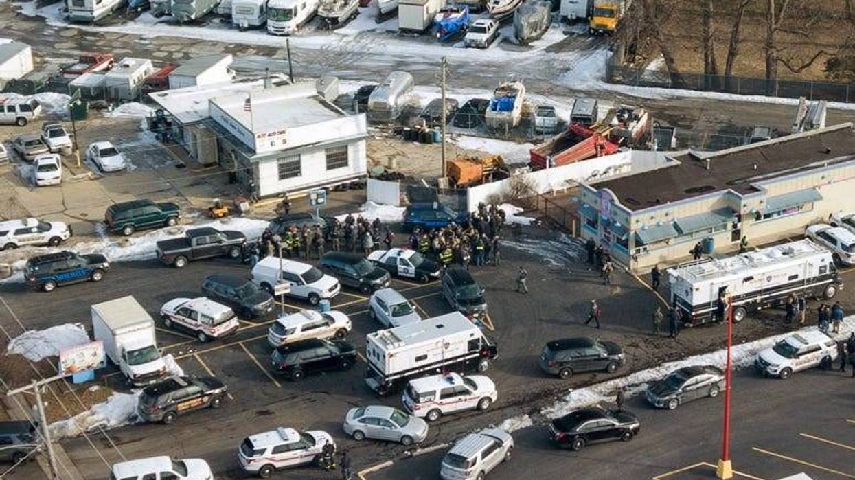 Law enforcement personnel gather near the scene of a shooting at an industrial park in Aurora