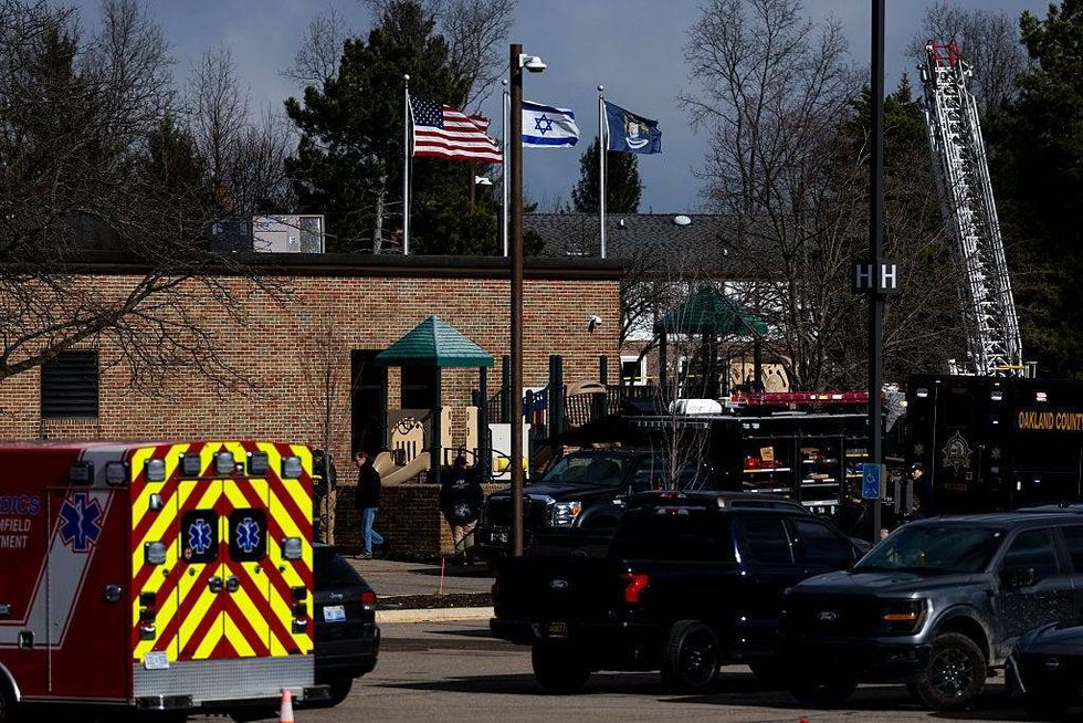 Law enforcement vehicles in the parking lot of Temple Israel as an Israeli flag blows in the wind on top of the building following an active shooter on March 12, 2026 in West Bloomfield
