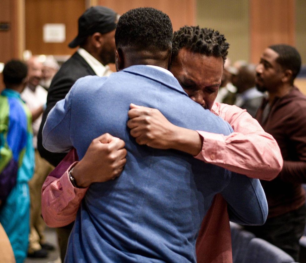 Lawrence E. Adjah (blue jacket) embraces a man at the Just Heal Bro conference for Black men