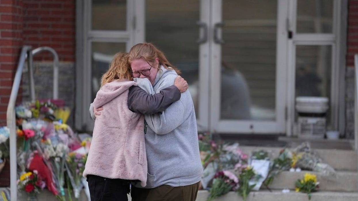 Leah Fauth gets a hug after leaving flowers in front of the West York Police Department after a police officer was killed responding to a shooting at UPMC Memorial Hospital in York, Pa., on Saturday.