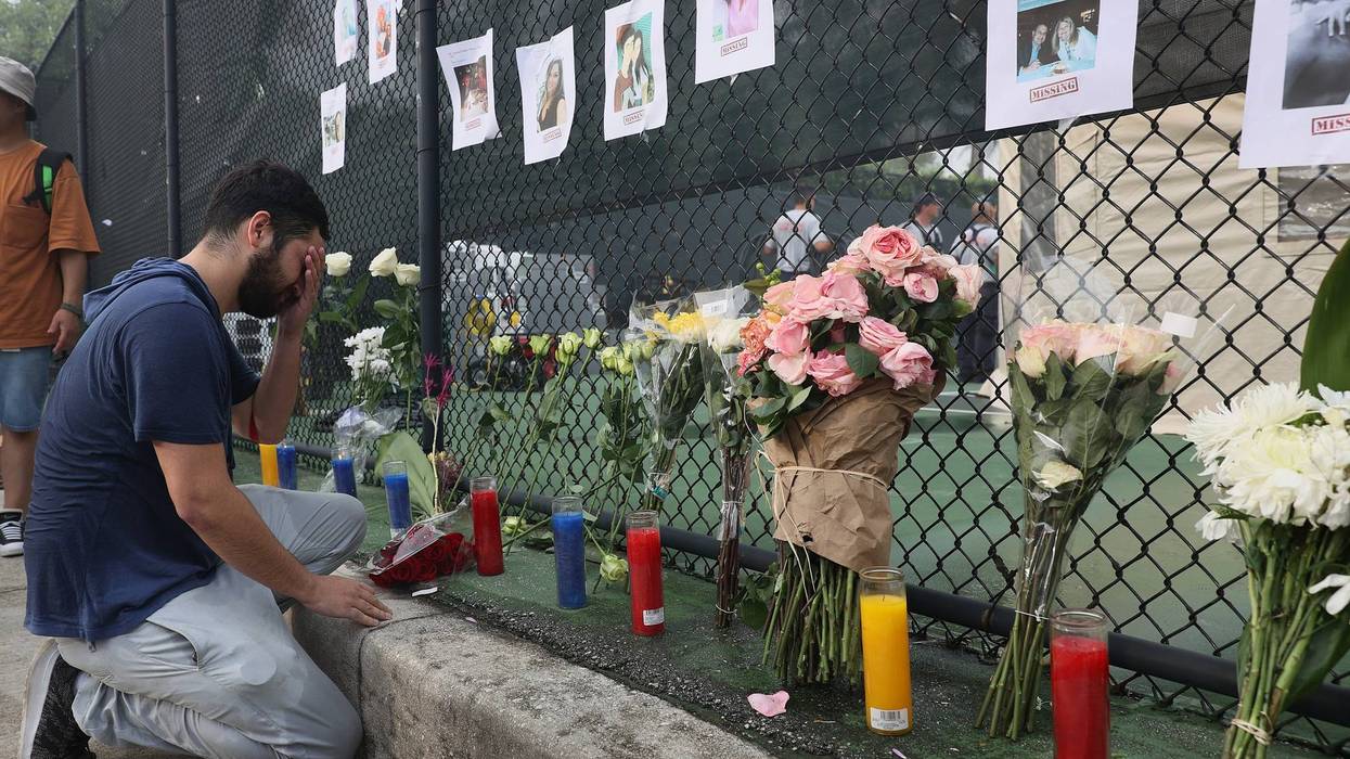 Leo Soto kneels in front of a memorial that includes pictures of missing people on June 25, 2021 in Surfside, Florida