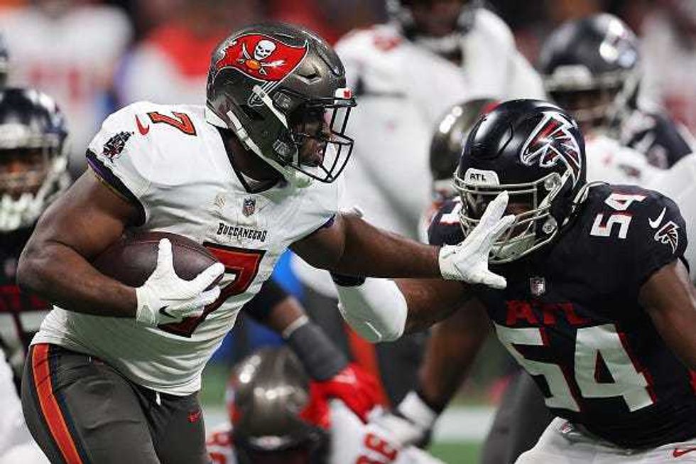 Leonard Fournette stiff arms a Falcons defender.