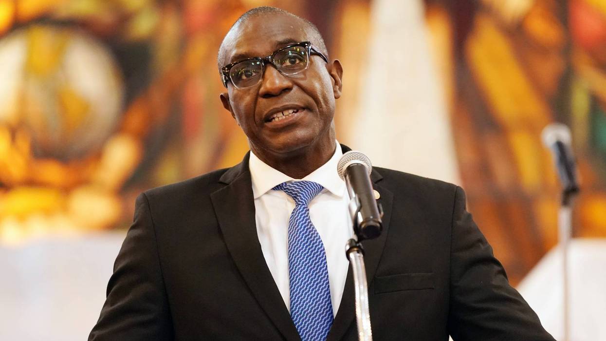 Lewis Reed stands at a podium in front of a blurred background.