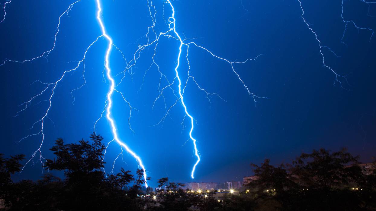 Lightning discharges during a large rainstorm in a city with forest fringes. Lightning rain in the city