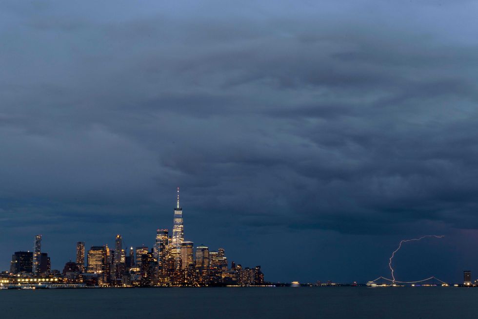 Lightning strikes behind the Verrazzano-Narrows Bridge as a thunderstorm passes by lower Manhattan and One World Trade Center in New York City on May 29, 2024, as seen from Hoboken, New Jersey