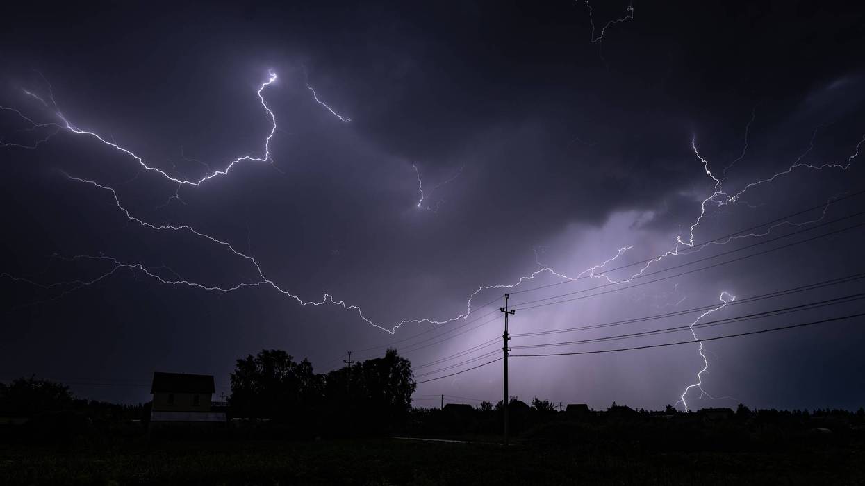 Lightning strikes illuminating night sky over rural landscape