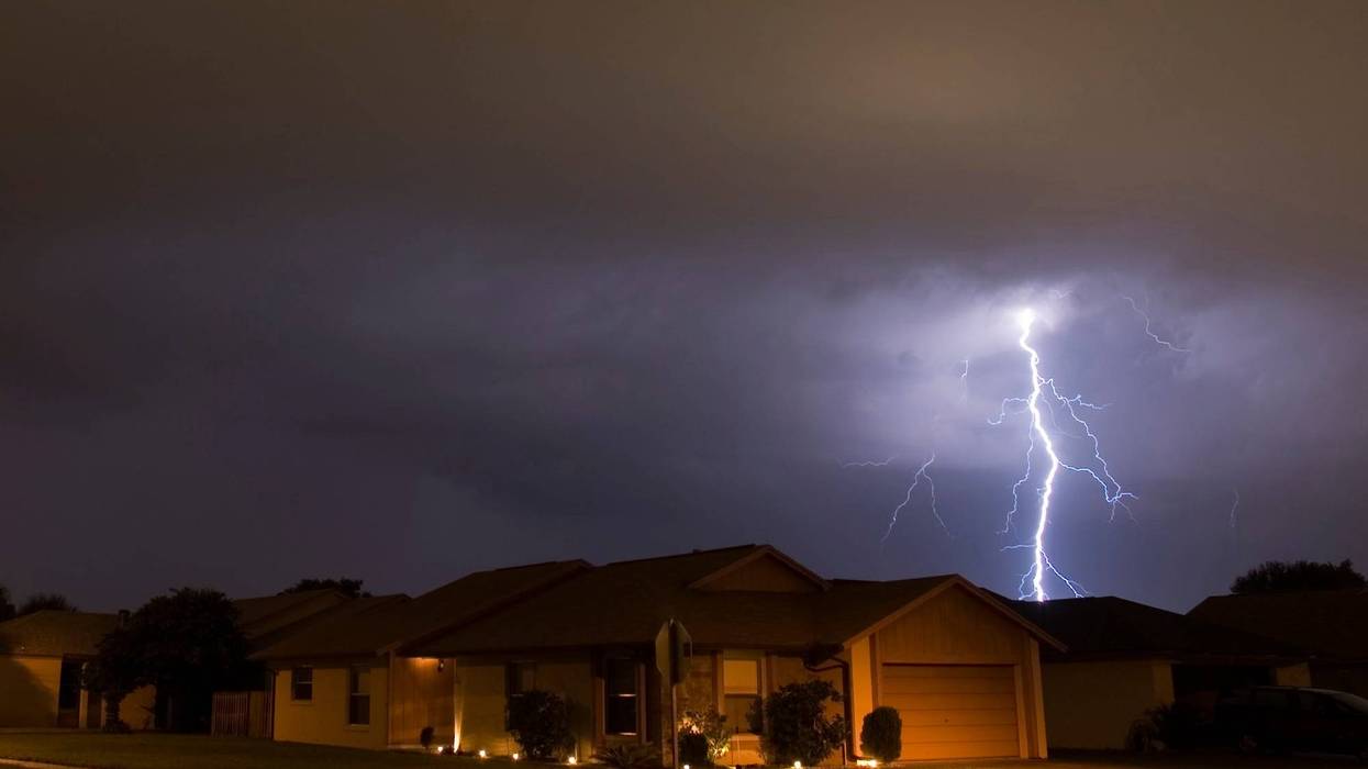 Lightning strikes in the night near family houses